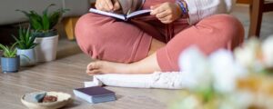 photo of woman sitting on ground with journal for Art of Manifestation: Master Turning Desires Into Reality